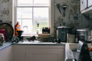 A person wiping down a kitchen countertop near a sink with a clean cloth.